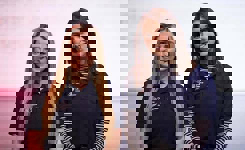 Two female One Dance UK dance ambassadors in blue t-shirts smiling at the camera