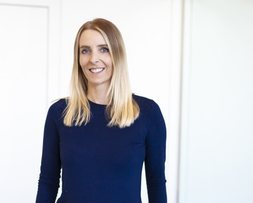 Headshot of Laura Nicholson. White female with long blonde hair wearing blue long sleeve tshirt  
